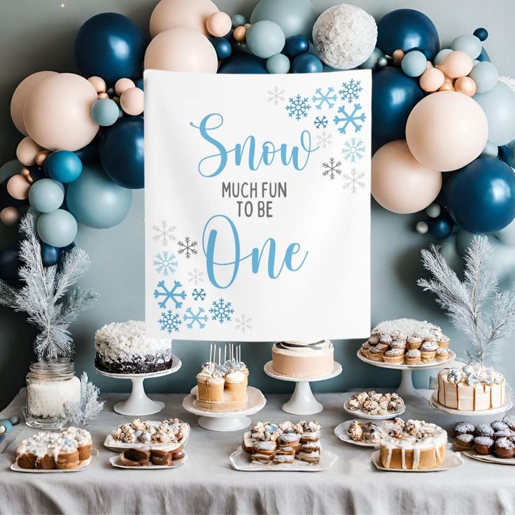 a snow much fun to be one sign surrounded by cakes and cupcakes on a table