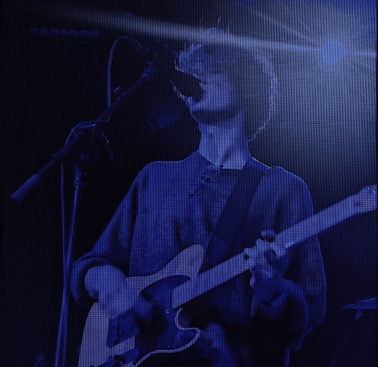 a man with a guitar in front of a microphone and some lights on the stage