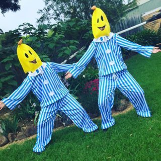 two people dressed in blue and white striped pajamas are holding hands while standing on the grass