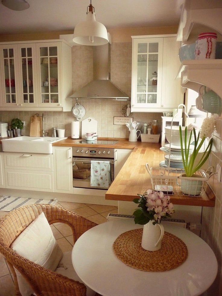 a kitchen filled with lots of white furniture and decor on top of a wooden table