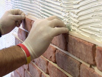 a brick wall being worked on by a person with gloves and rubber band around it