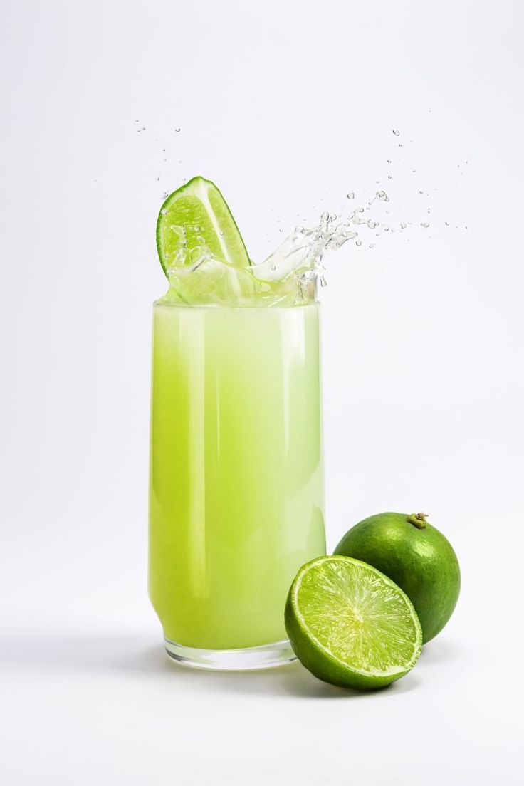 a green drink with limes splashing out of it