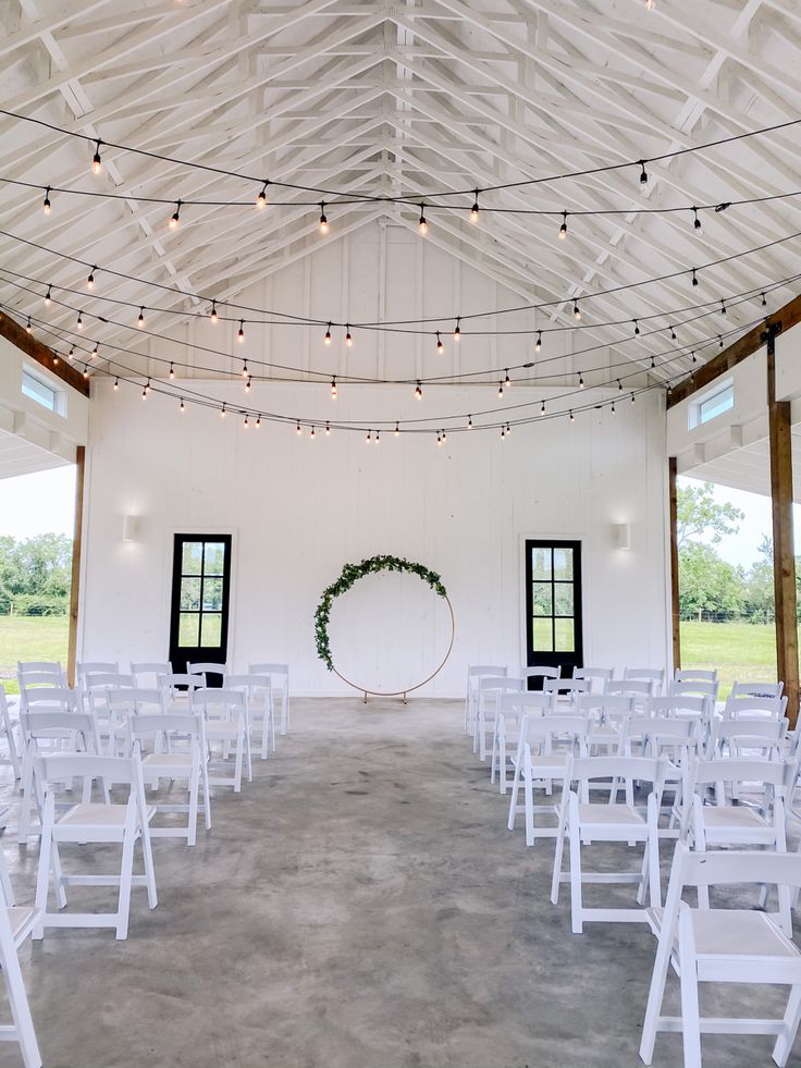 an indoor venue with white chairs and string lights