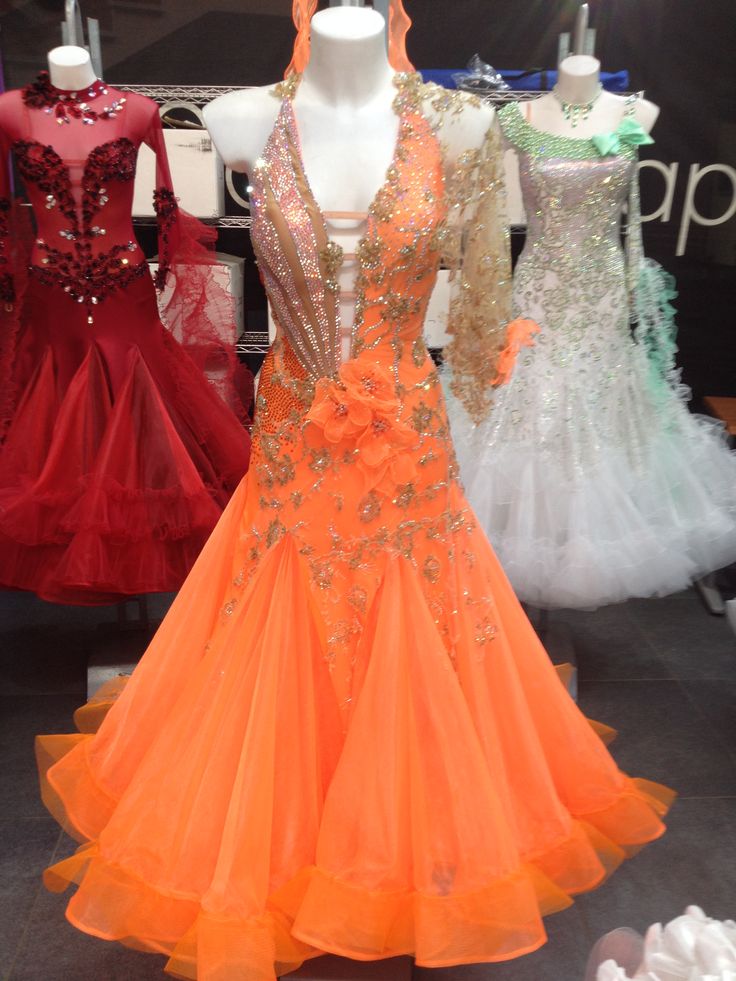 dresses on display in a store window with mannequins and other items behind them