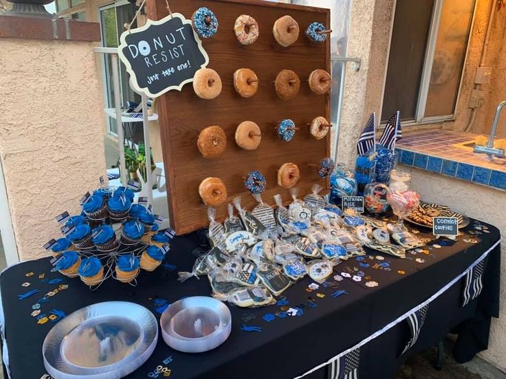 a table topped with lots of donuts and cupcakes next to a sign