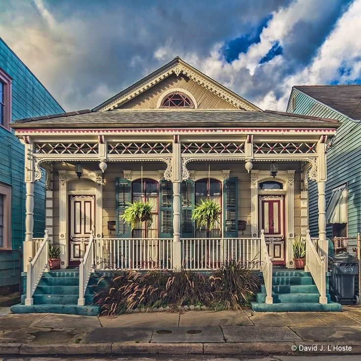 an old house with blue shutters on the front porch and steps leading up to it