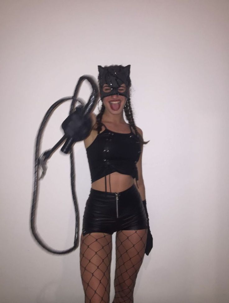 a woman wearing a black cat mask and fishnet tights with a whip in her hand