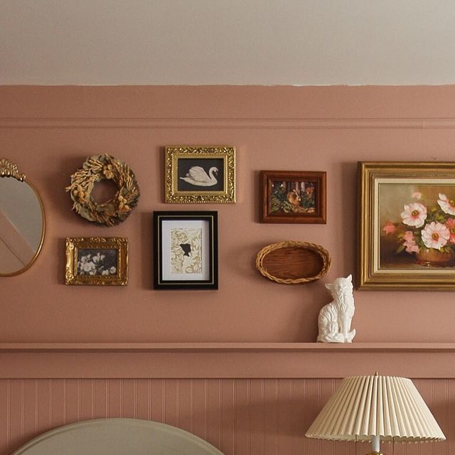 a bedroom with pink walls and pictures on the wall