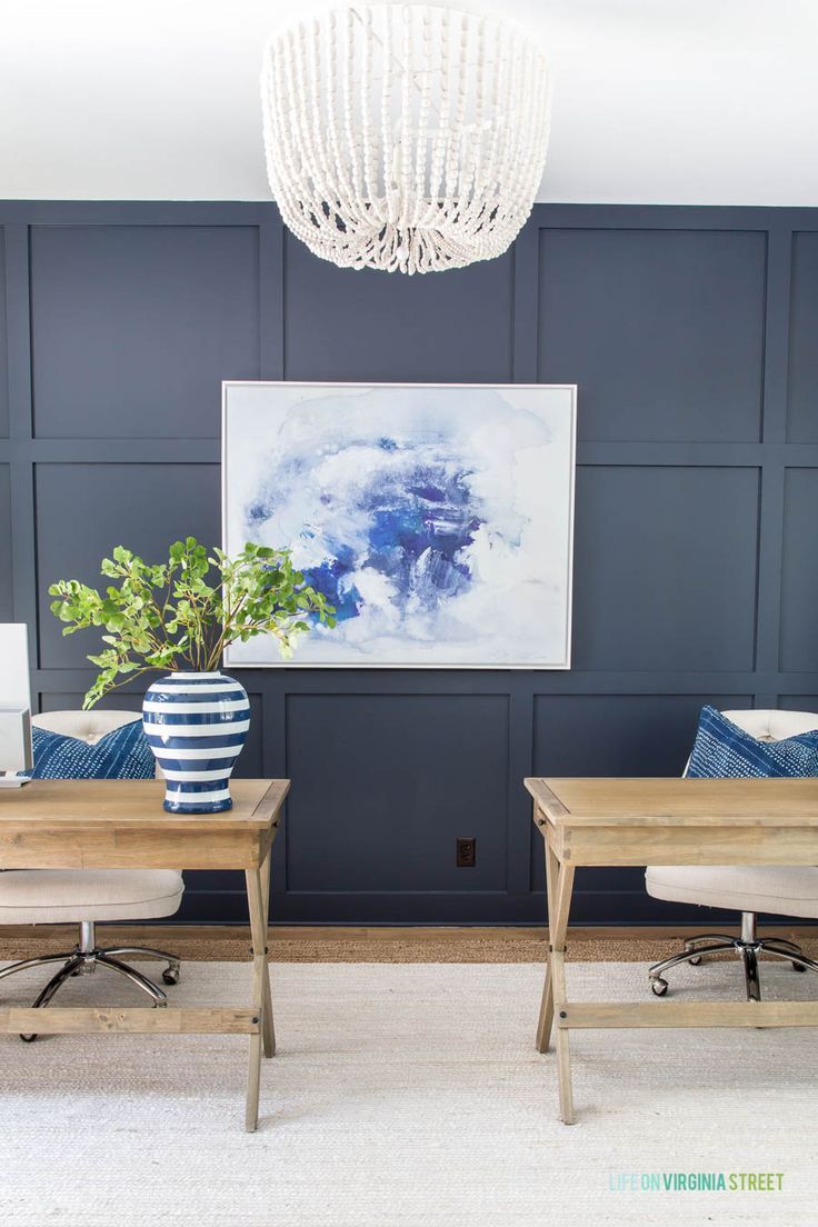 two wooden desks in front of a blue wall with a white chandelier