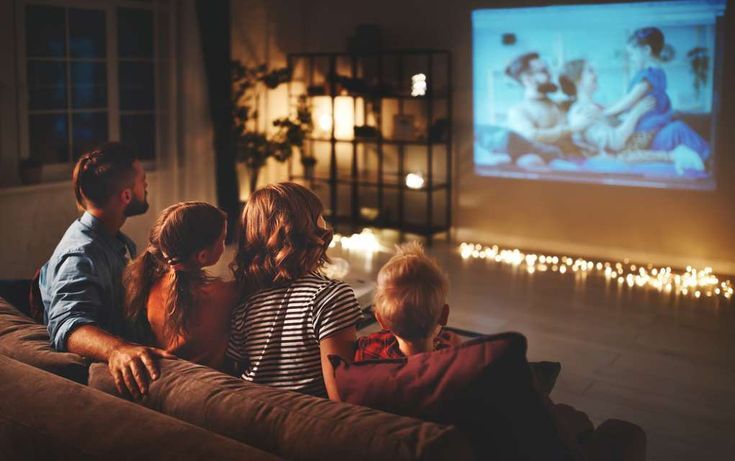 family sitting on couch watching movie in living room