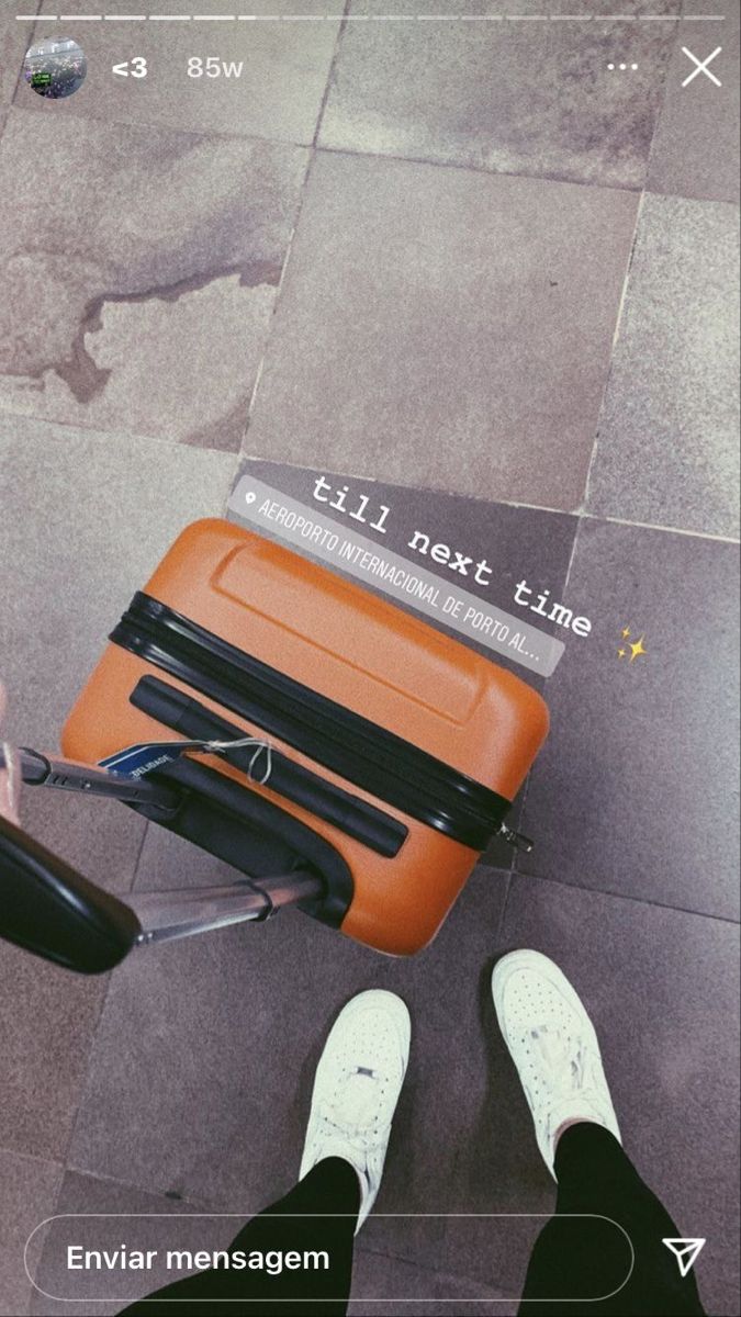 an orange piece of luggage sitting on top of a floor next to someone's feet