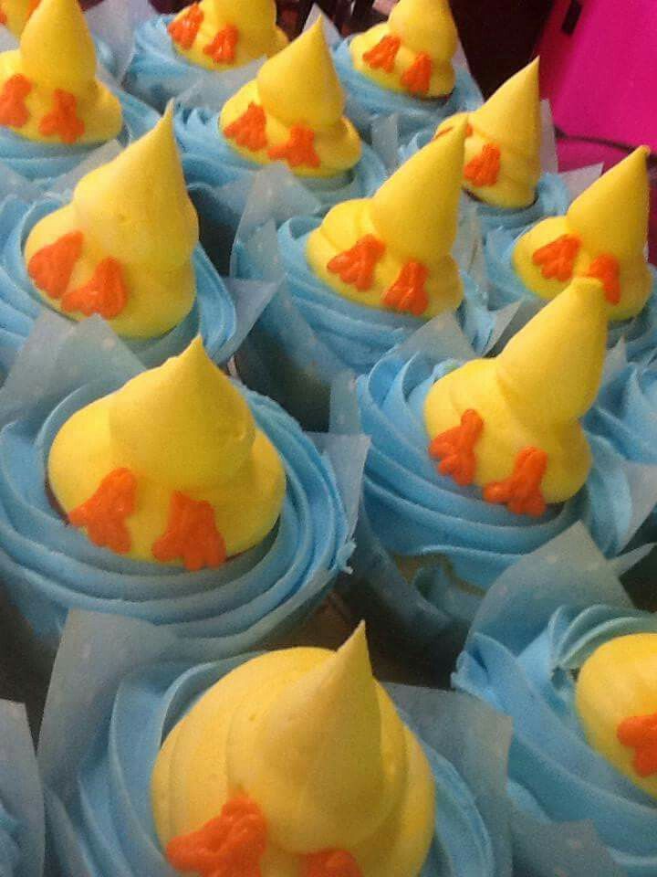 several cupcakes with yellow frosting and orange decorations on blue paper wrappers