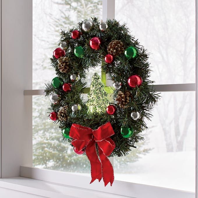 a christmas wreath hanging on a window sill