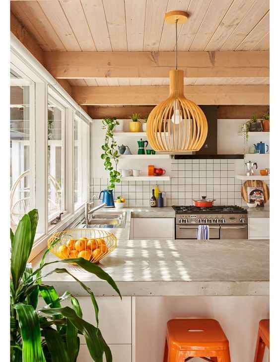 a kitchen with an island and orange stools in front of the stove top oven