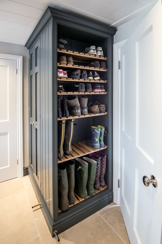 an open shoe cabinet with many pairs of boots on the bottom shelf and two doors