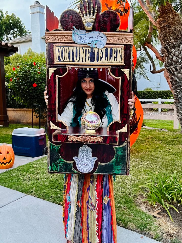 a woman is holding up a costume that looks like an old fashioned phone booth with the words fortune teller on it