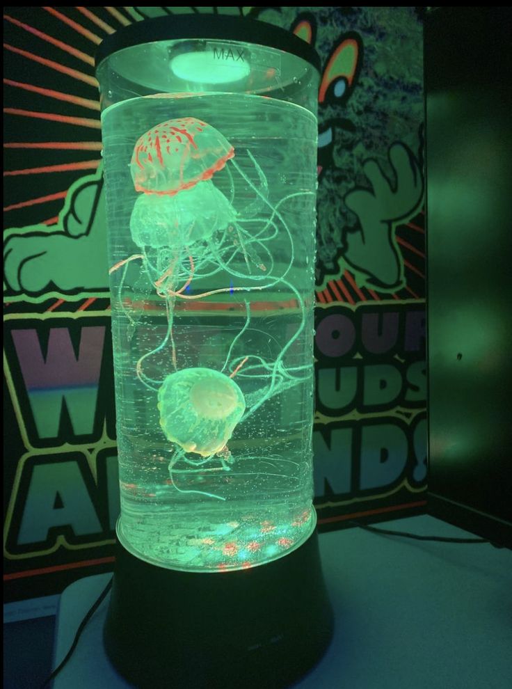 an illuminated jellyfish in a glass container on top of a black stand with neon lights