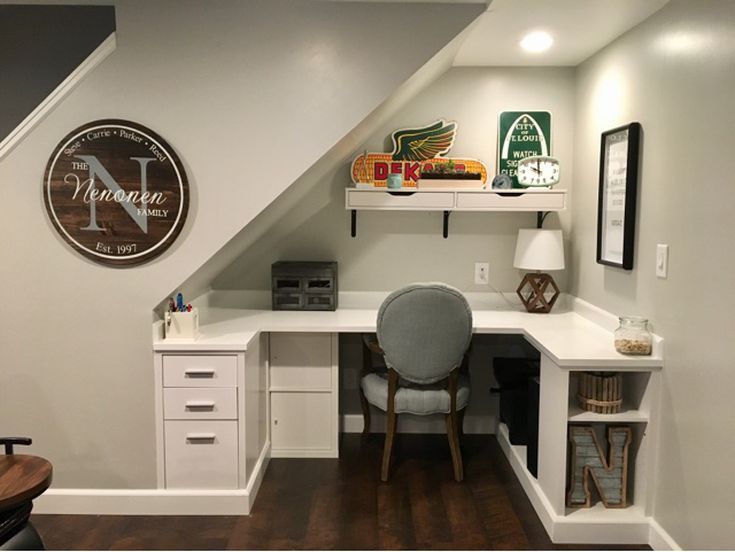 a desk with a chair underneath it under a slanted ceiling in a home office