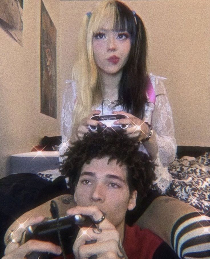 two people are playing video games on the bed while one person is taking a selfie