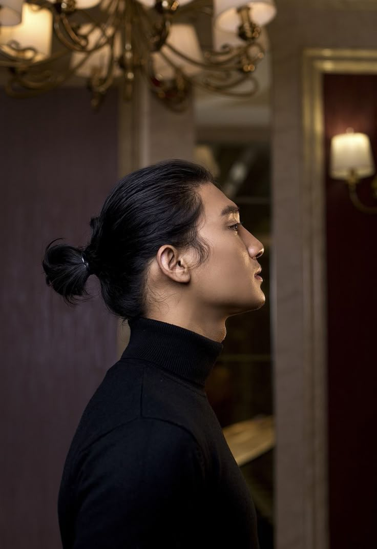 a woman standing in front of a chandelier with her head turned to the side