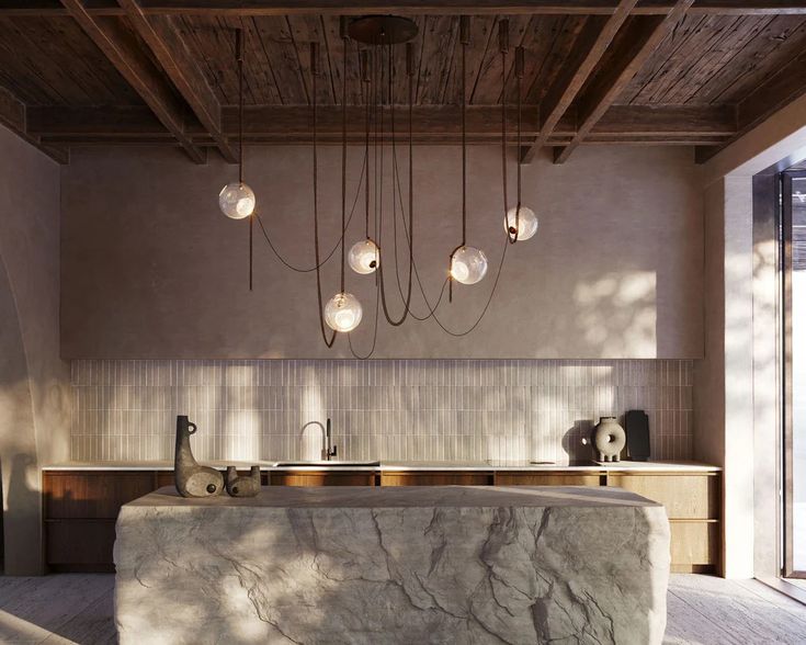 a kitchen with marble counter tops and lights hanging from the ceiling