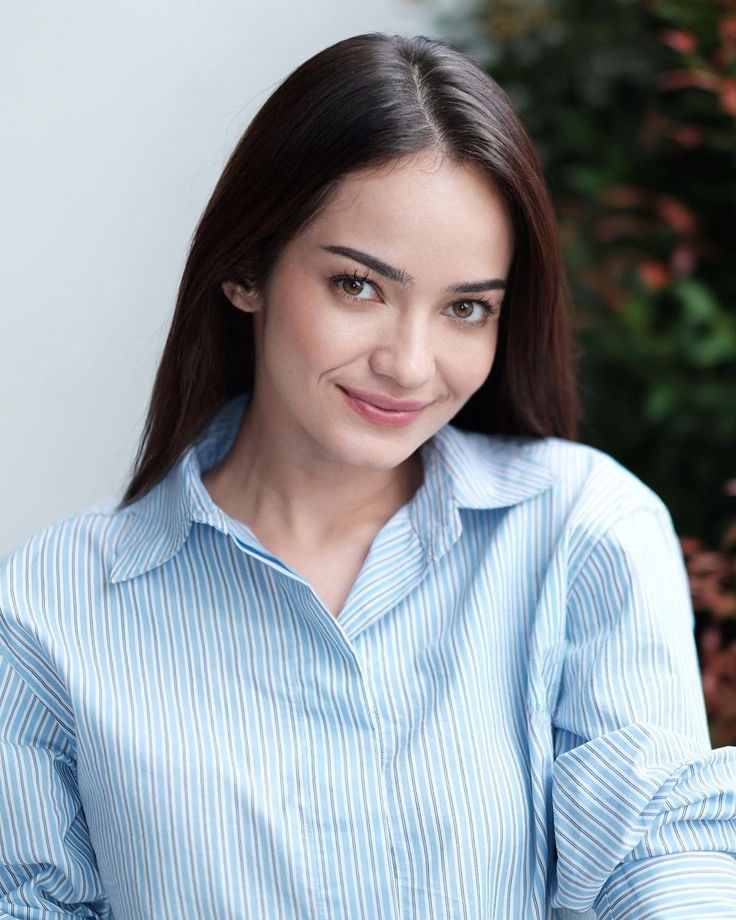 a woman in a blue shirt is smiling at the camera