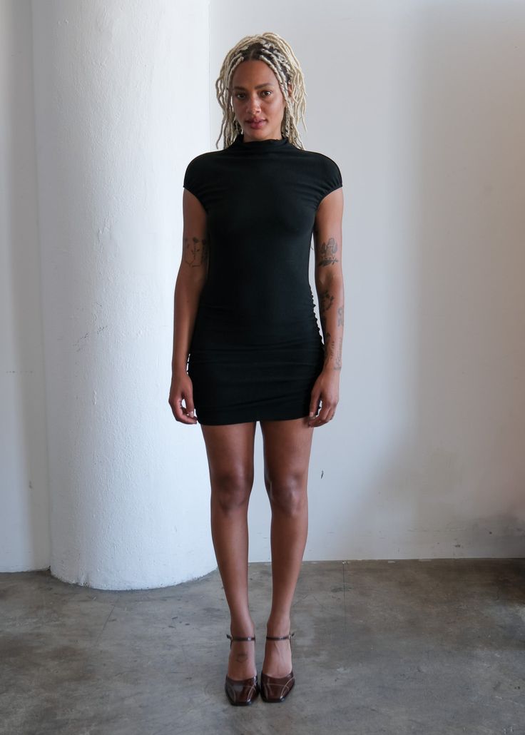 The Lorrie Dress is a medium-weight mock neck, ruched mini dress featuring a cap sleeve with an elastic finish. Black Dress With Accessories, Dress With Loafers, 90s Models Off Duty, Zodiac Aesthetic, Style Roots, 90s Model, Ruched Mini Dress, Office Siren, Grad Dresses