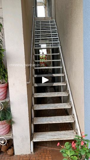 a set of stairs leading up to the top of a building with potted plants on either side