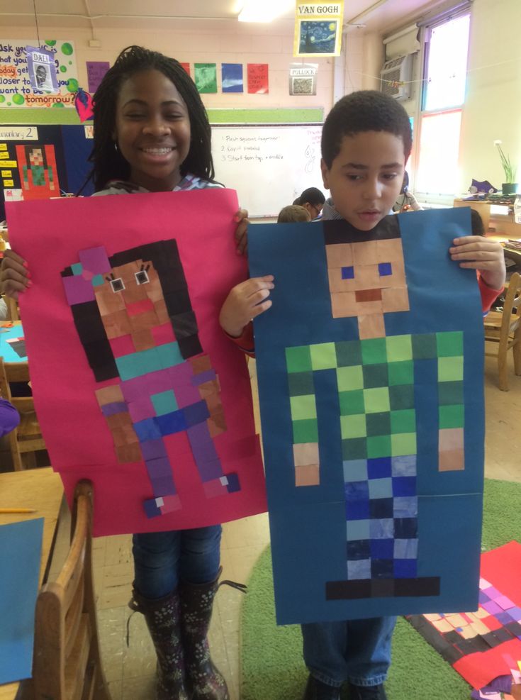 two children holding up paper cutouts made to look like minecrafts in the classroom