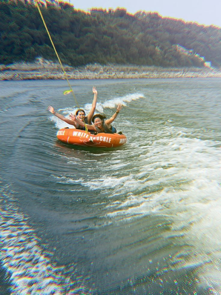 two people on an inflatable tube being pulled by a boat