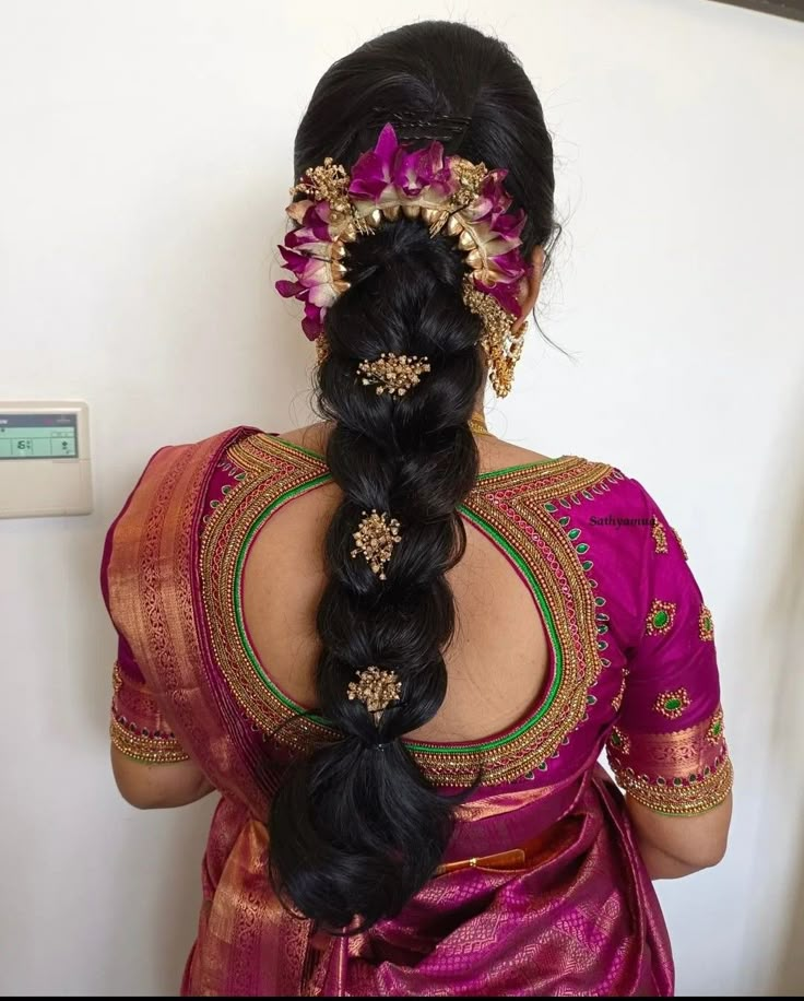 a woman with long black hair wearing a pink sari