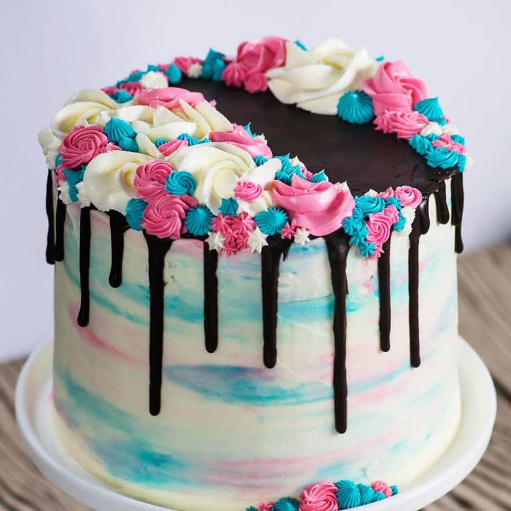 a cake decorated with pink, blue and white icing on top of a wooden table