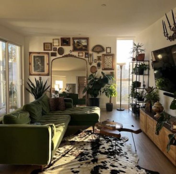 a living room filled with lots of furniture and plants on the wall above it's tv