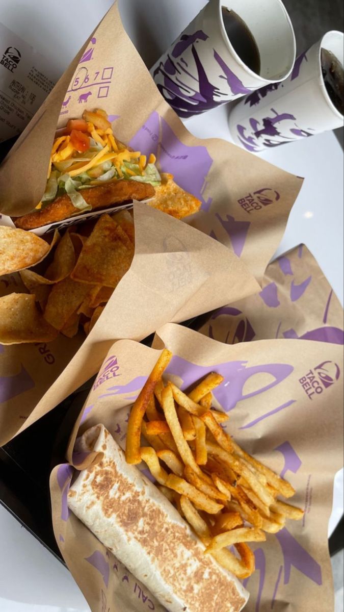 two sandwiches and french fries in paper wrappers