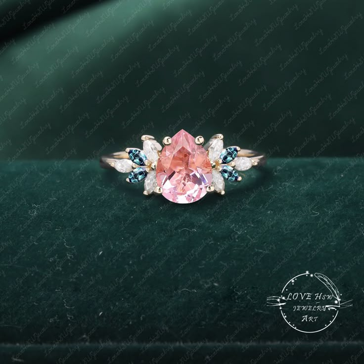 an engagement ring with pink sapphire and blue topaztes on green velvet background, close up