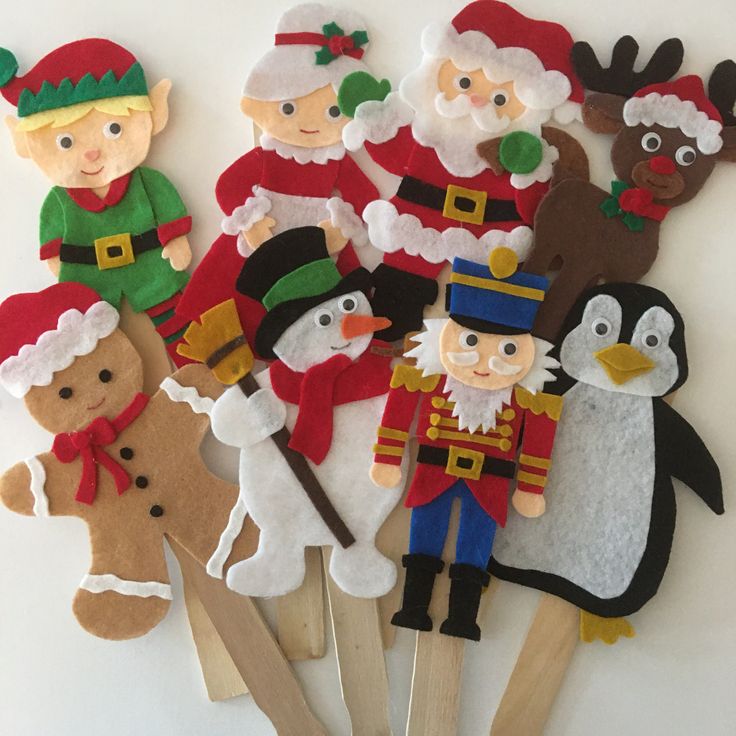 a group of felt christmas decorations on wooden sticks