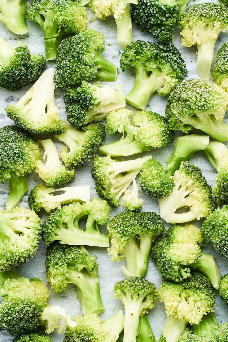 broccoli florets on a white surface with sprinkles and seasoning