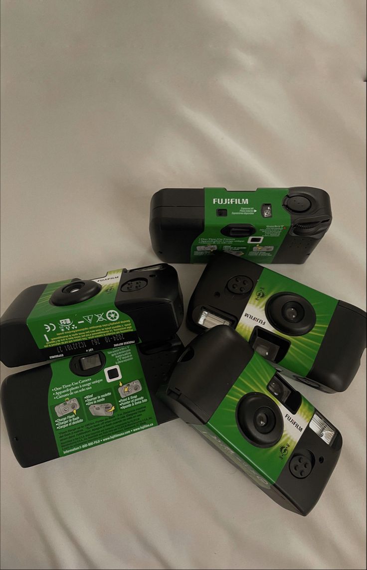 four black and green cameras sitting on top of a bed