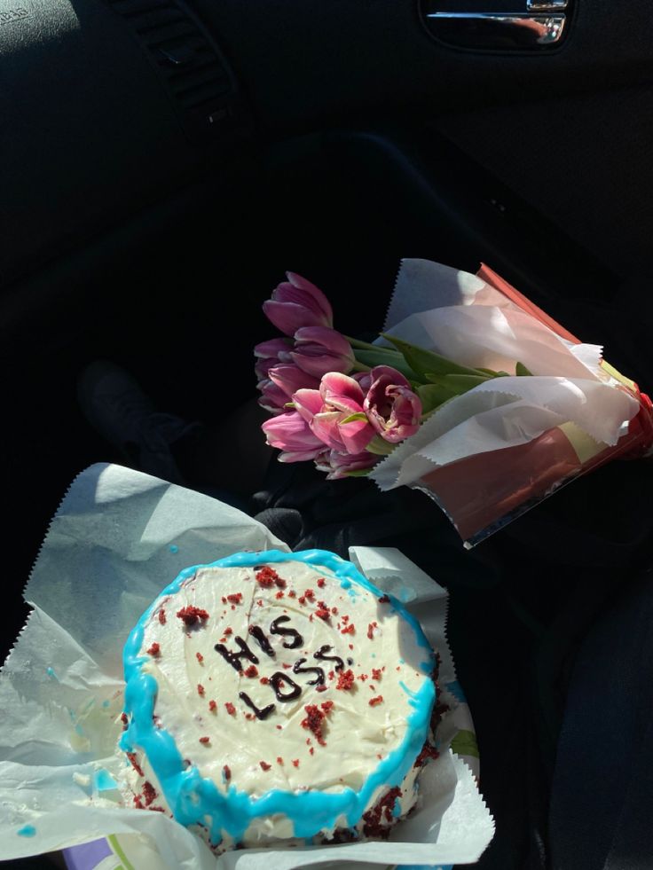 the birthday cake is decorated with blue icing and pink tulips on the table