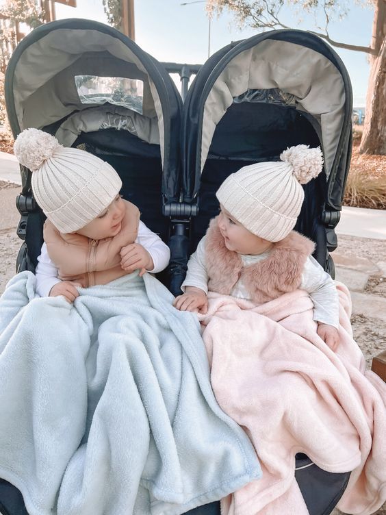 two babies sitting in strollers with blankets on them