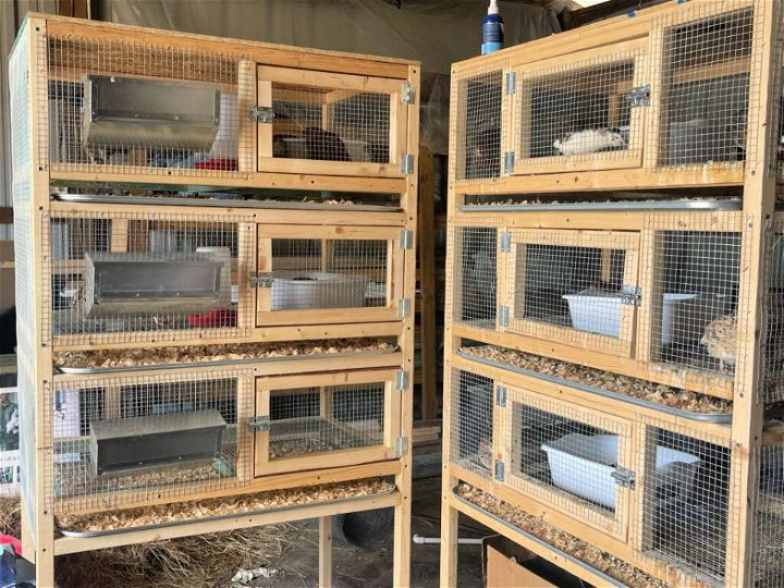 two wooden cages filled with birds inside of a building