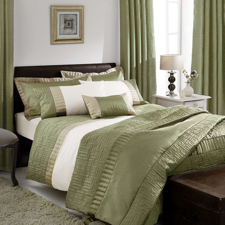 a bed with green and white comforters in a bedroom