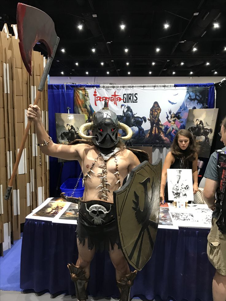 a man dressed up as a gladiator at a booth with other people standing around