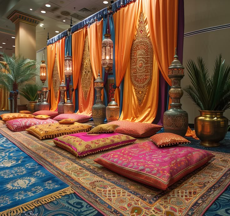 a room filled with lots of pillows on top of a blue carpet covered in orange drapes