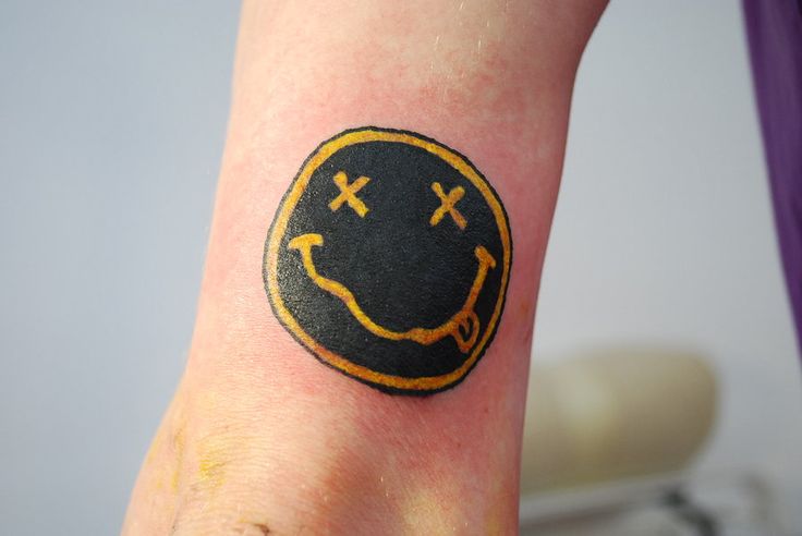 a smiley face tattoo on the left arm