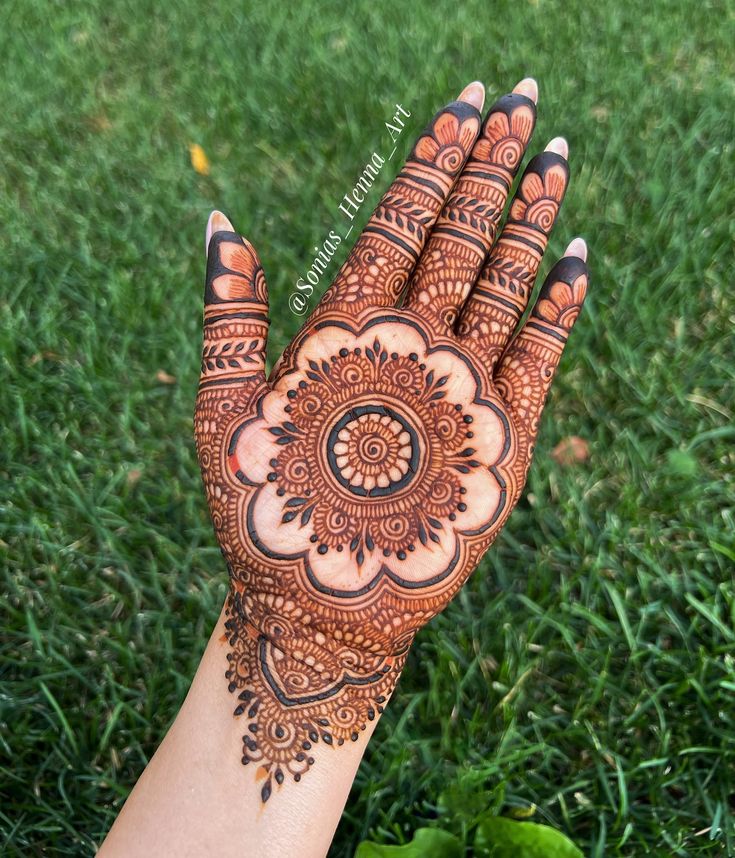 a hand with henna on it in the grass