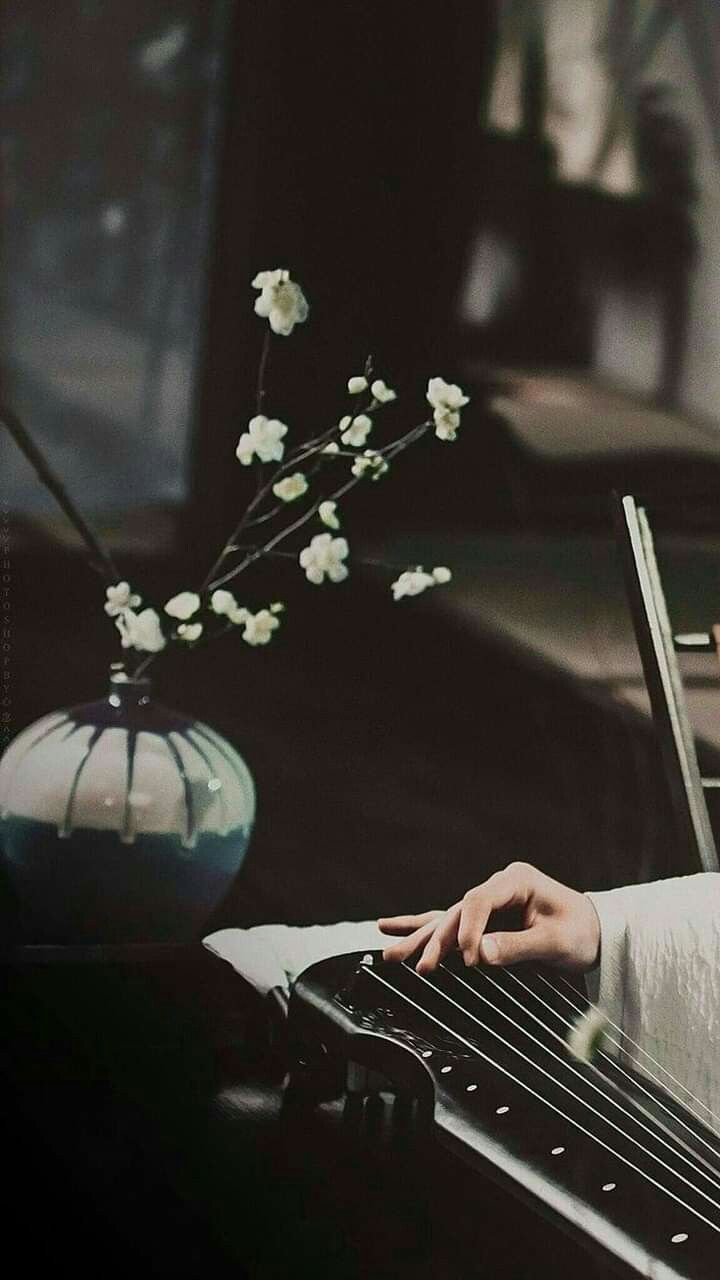 a woman sitting at a piano with her hand on the keyboard and flowers in front of her