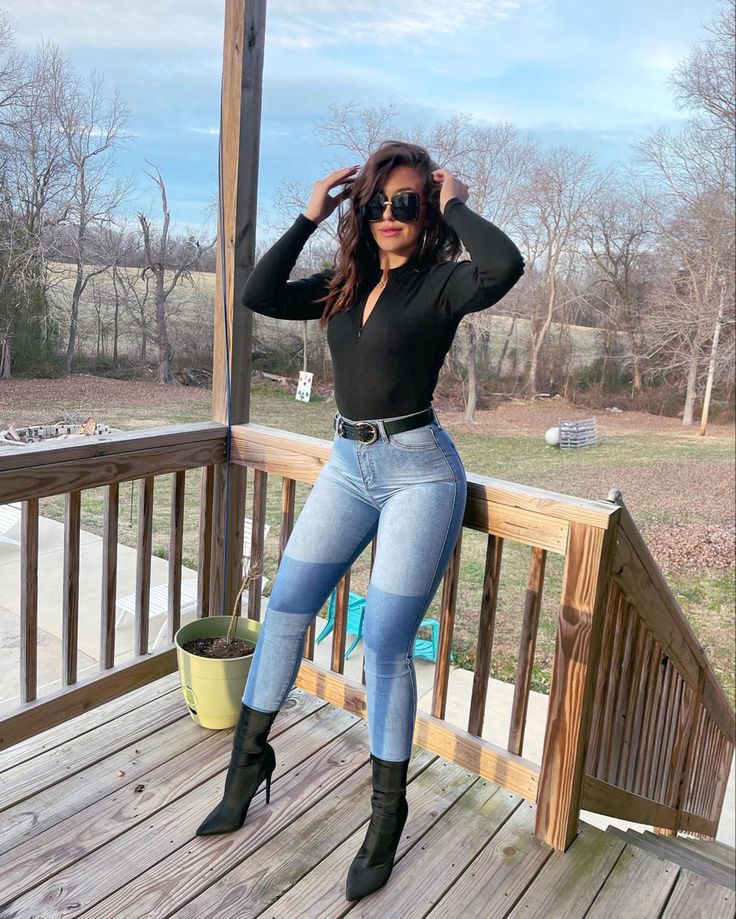 a woman in black shirt and jeans posing on porch