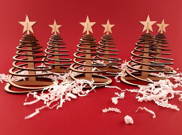 several wooden christmas trees with star decorations on red background, surrounded by shredded white paper