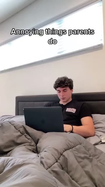 a man sitting in bed using a laptop computer with the caption, amenving things parents do